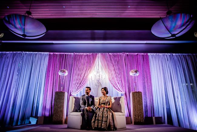 Indian reception stage with purple and blue lighting and lounge sofa