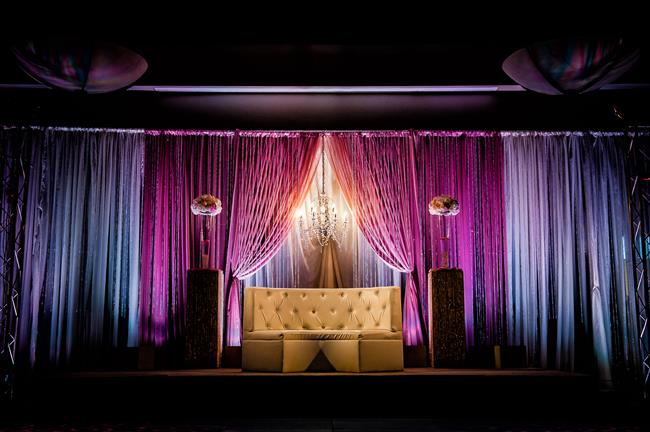 Indian reception stage with white sofa and pink and blue uplighting